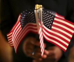 A woman holds a cluster of U.S. flags during a U.S. Citizenship and Immigration Services naturalization ceremony in Oakland